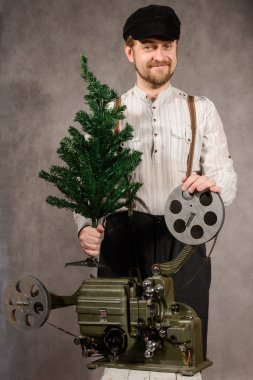 Cheerful projectionist with Christmas tree in their hands