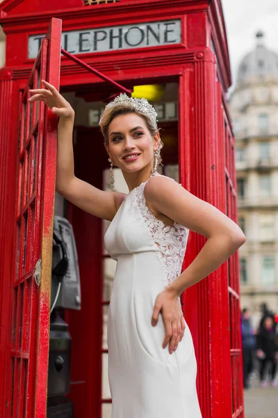 Panna Młoda Białej Sukience Stoi Czerwonej Budce Telefonicznej — Zdjęcie stockowe