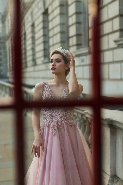 Stock image The bride in a powder dress stands in front of the telephone cabin, looking away