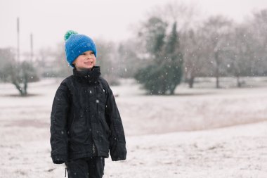 Siyah ceketli çocuk kışın gülümsüyor.