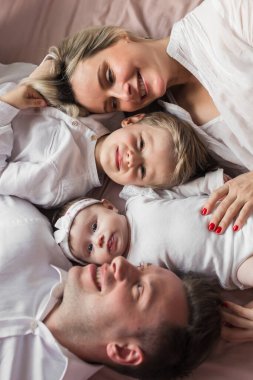 Anne ve baba ve çocukları yataktalar. Baba, anne, oğul ve küçük kız. Kapat..