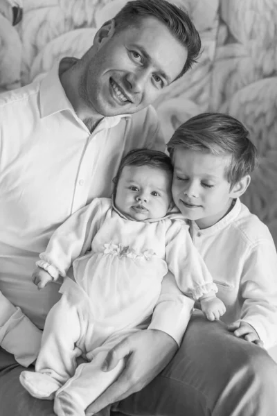 A happy family. Father son and daughter toddler. Father holds daughter in his arms. Black and White. Exemplary family.