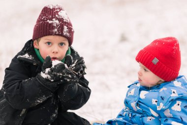 Mutlu çocuklar kışın dışarıda oynayarak eğleniyorlar. Kış tatilleri ve tatiller. Karları üfleyen çocuk..
