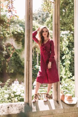 Puantiyeli elbise giymiş şık bir kadın. Güzellik. Puantiyeli elbise. Puantiyeli Burgundy. Büyürken. Arkaplan mimarisi. Gotik mimari.