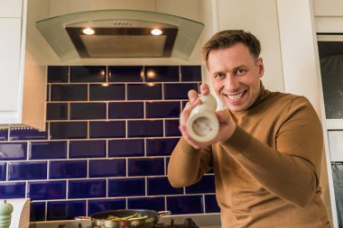 Elinde biberlik tutan genç bir adam. Kameraya bakıyorum. Bir şef oyunu. İçeri gir. Mutfak..