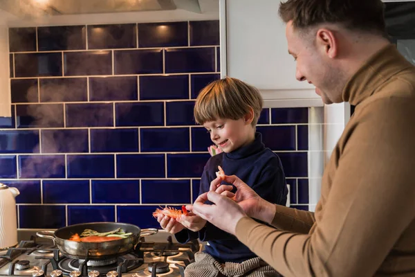 幸せな家族だ 父と息子は鍋でおいしい食事を準備します 魚介類 — ストック写真