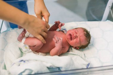 Hemşire yeni doğmuş bir bebek gibi giyiniyor. Doğumdan saniyeler sonra yeni doğan bebek.