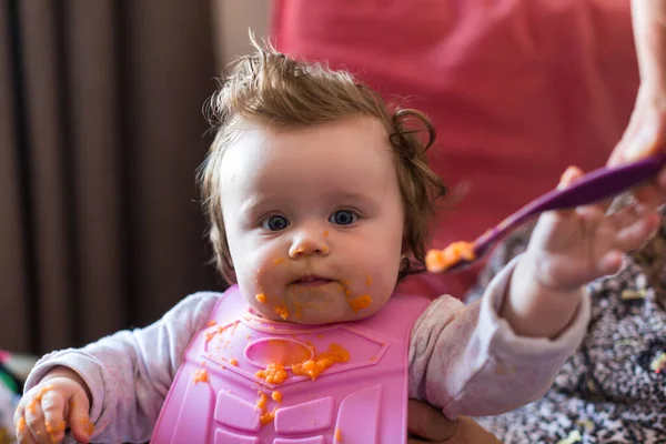 小さな金髪の幼児の少女の肖像画 スプーンを食べる 汚い口だ ママは赤ん坊を養う — ストック写真