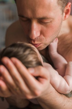 Çıplak baba kucağında onu öpen çıplak bir bebek tutuyor. 3 aydır. Kapalı.