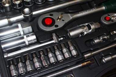 Siyah plastik bir kutuya yerleştirilmiş profesyonel bir anahtarın yüksek açılı yakın çekimi. Kırmızı düğmeli mandallar, dahili eklentiler ve çeşitli bitler gibi organize araçlar, otomotiv onarımı ve profesyonel bakım projeleri için mükemmeldir..