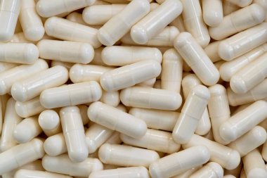 Beyaz vitamin takviye kapsülleri dağınık, düz zemin biçimi.