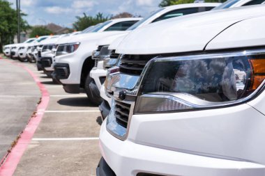 White generic fleet SUV's parked in a lot, side closeup on front of vehicle with focus on foreground. Transportation and logistics industry. clipart