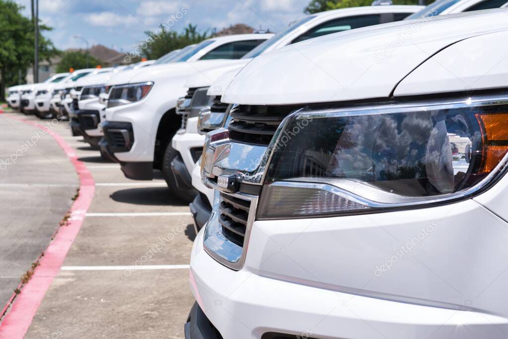 White generic fleet SUV's parked in a lot, side closeup on front of vehicle with focus on foreground. Transportation and logistics industry.