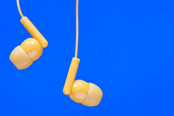 Orange Colored Earbuds Closeup Plain Blue Background Copy Space Audio — Stock Photo, Image