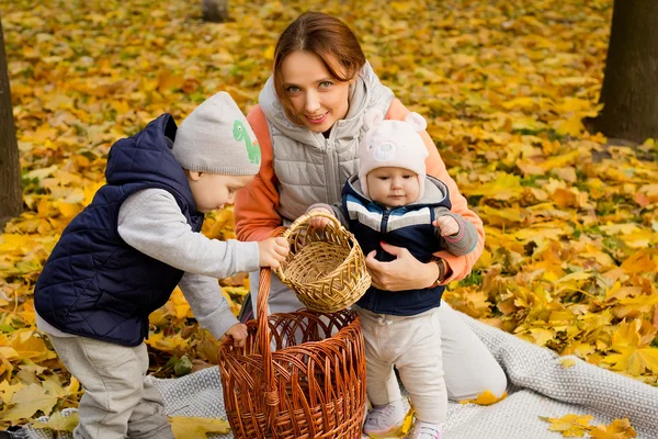 Jonge moeder met haar kinderen in het najaar park — Stockfoto