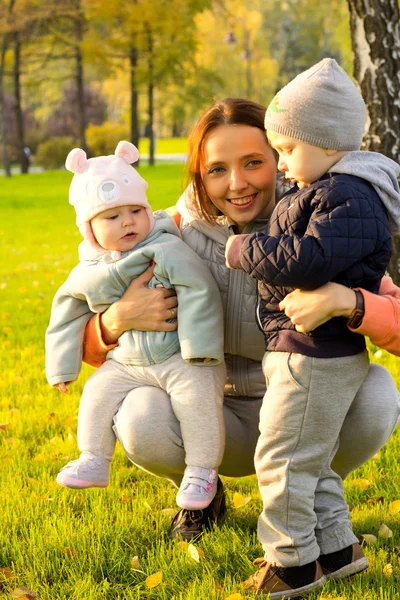 Jonge moeder met haar kinderen in het najaar park — Stockfoto