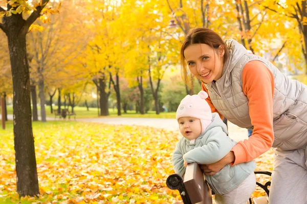 Jonge moeder met haar kinderen in het najaar park — Stockfoto