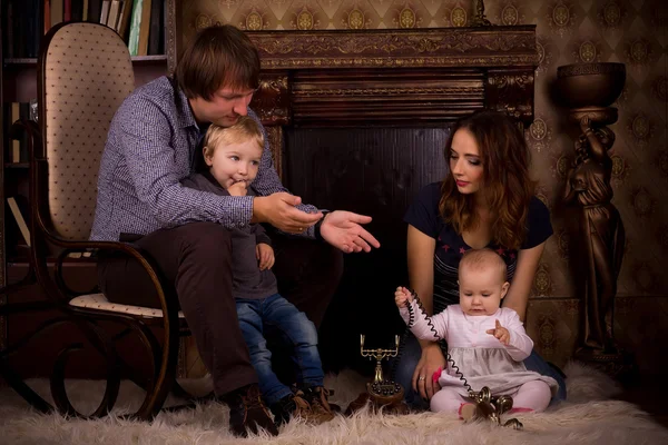 Familie auf einem flauschigen Teppich am Kamin — Stockfoto