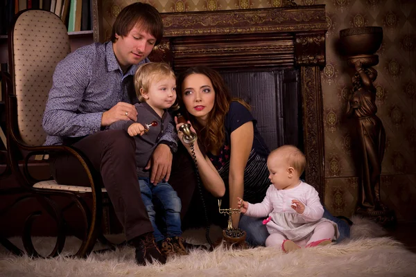 Familia en una alfombra esponjosa junto a la chimenea — Foto de Stock