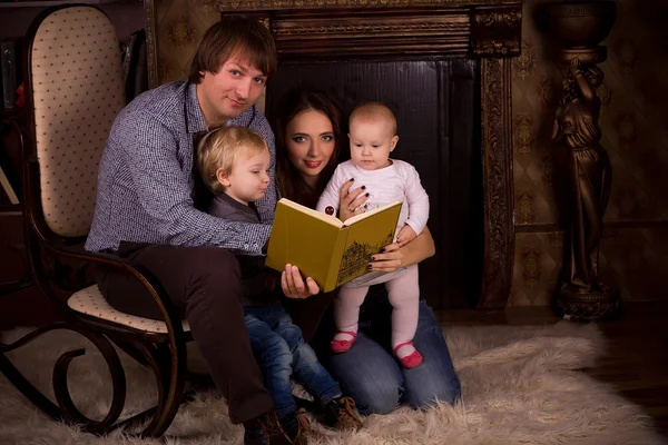 Familie op een pluizige tapijt bij de open haard — Stockfoto