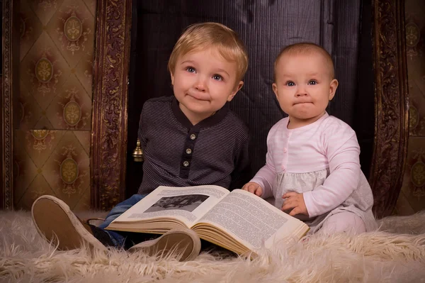 Barn på en fluffig matta med bok — Stockfoto