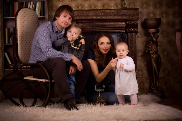 Familia en una alfombra esponjosa junto a la chimenea — Foto de Stock