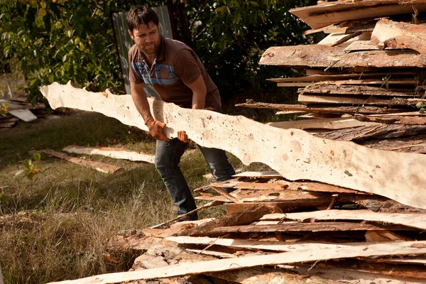 Snickare bär en stor trä planka på händerna — Stockfoto