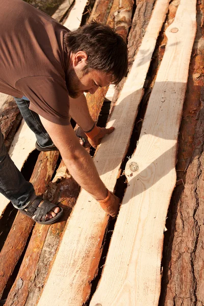 Hombre pilas de tablones de madera — Foto de Stock