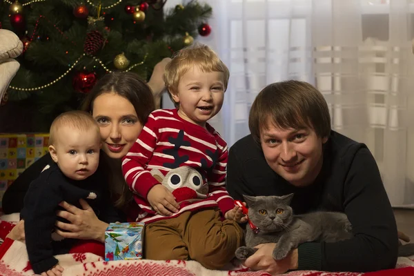 Familia feliz con el bebé bajo el árbol de Navidad decorado, regalos —  Fotos de Stock