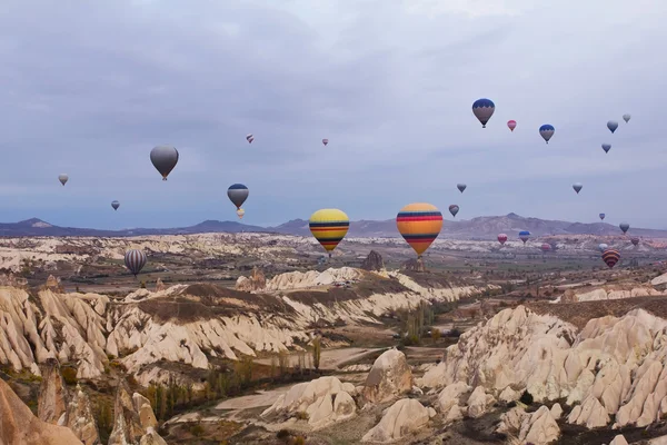 Kapadokya Türkiye 'de kayaların üzerinde uçan sıcak hava balonu