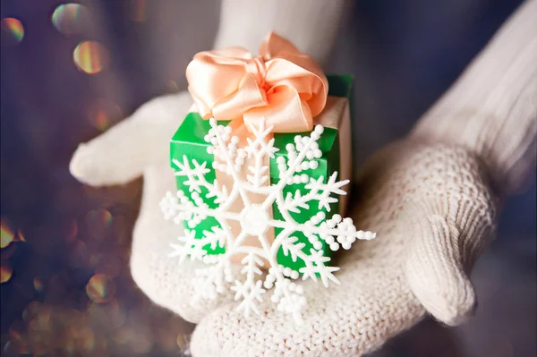 Gift in hands with mittens on winter magic background — Stock Photo, Image