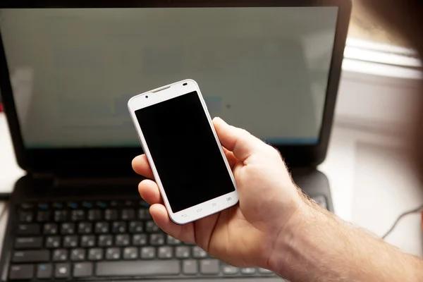 Homem usando smartphone, close-up, notebook em segundo plano — Fotografia de Stock