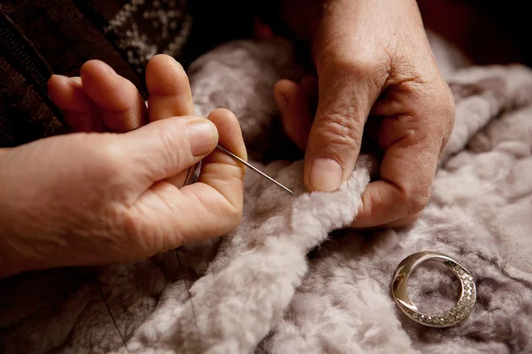 Handen van een oudere vrouw voor het naaien Stockfoto