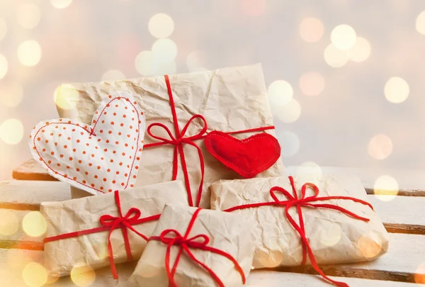 Gift boxes and hearts on white wooden background — Stock Photo, Image