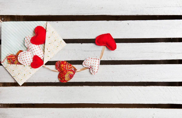 Lot of hearts in envelope on white wooden background — Stock Photo, Image