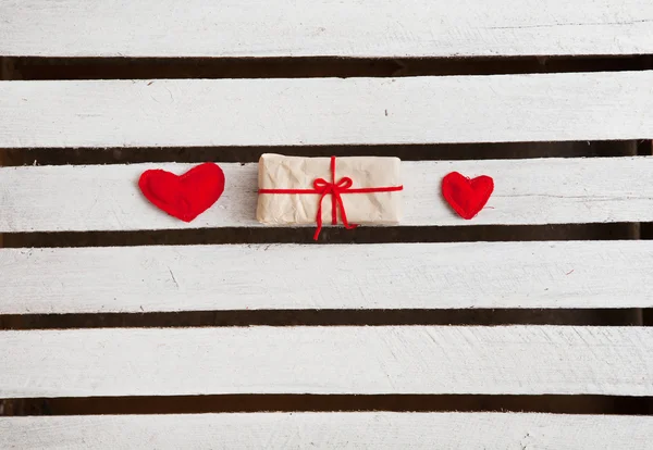 Two red hearts and gift on white wooden background — Stock Photo, Image