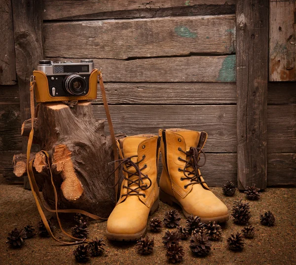 Stilleven met laarzen en retro camera op houten achtergrond — Stockfoto