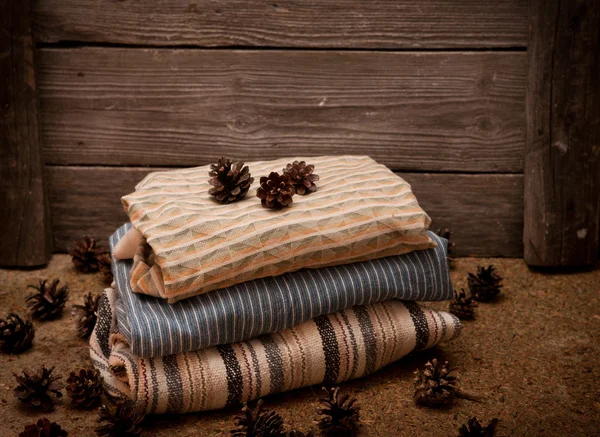 Pile of clothes with pine cones on wooden background — Stock Photo, Image