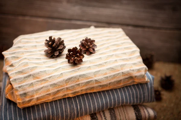 Pile of clothes with pine cones on wooden background — Stock Photo, Image