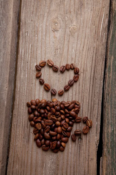 Café en grains et tasse sur fond en bois — Photo