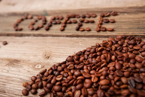 咖啡豆和木制背景上的杯子 免版税图库图片