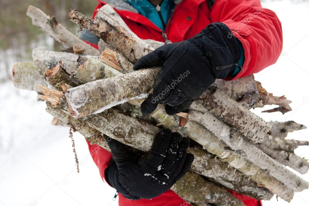 bearded man with firewood in winter forest