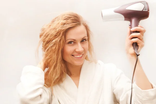 Hermosa mujer secándose el cabello con secador de pelo — Foto de Stock