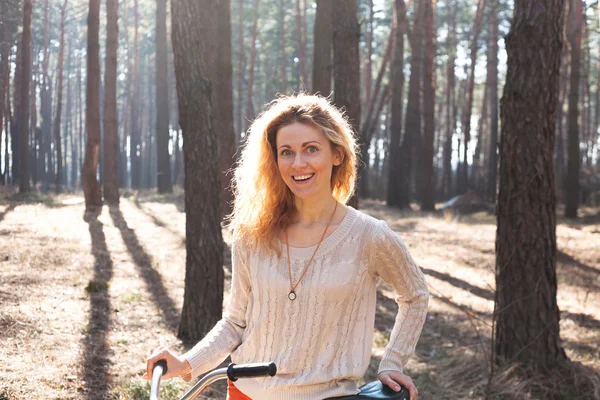 Beautiful young woman on bike in sunny park — Stock Photo, Image