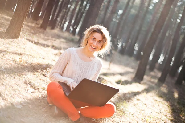 Sonriente chica joven con ordenador portátil al aire libre — Foto de Stock