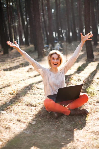 Sonriente chica joven con ordenador portátil al aire libre — Foto de Stock