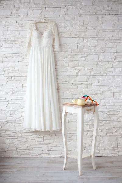 Piękna suknia ślubna na wieszak biały mur — Zdjęcie stockowe