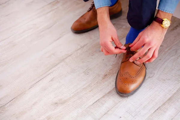 Крупним планом чоловіча нога і руки зав'язують взуття мереживами — стокове фото