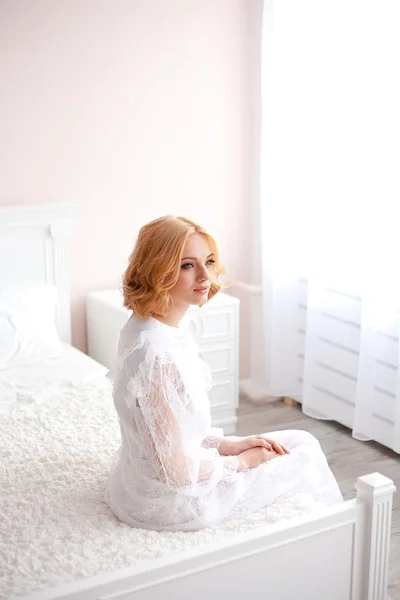 Beautiful blonde girl woke up and sitting on a bed — Stock Photo, Image