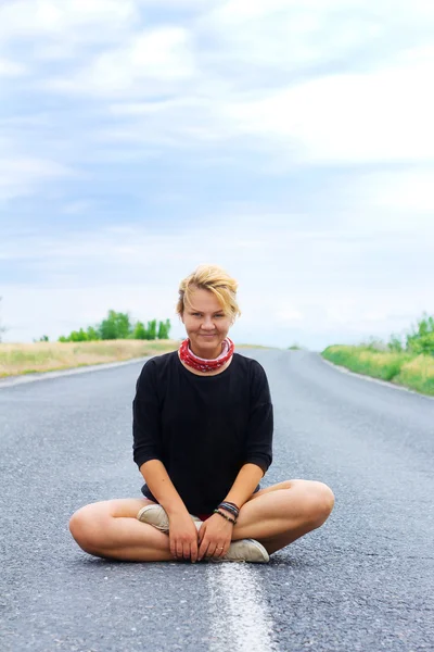 Young woman smile in lotus position on the road — Zdjęcie stockowe